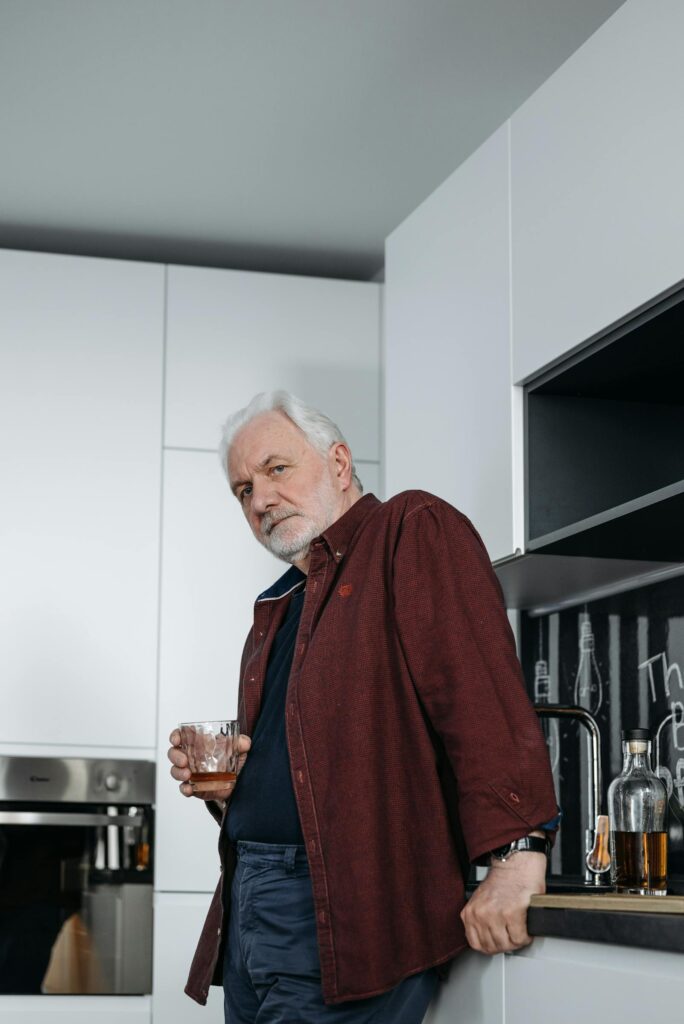 An elderly woman in her quiet home kitchen.