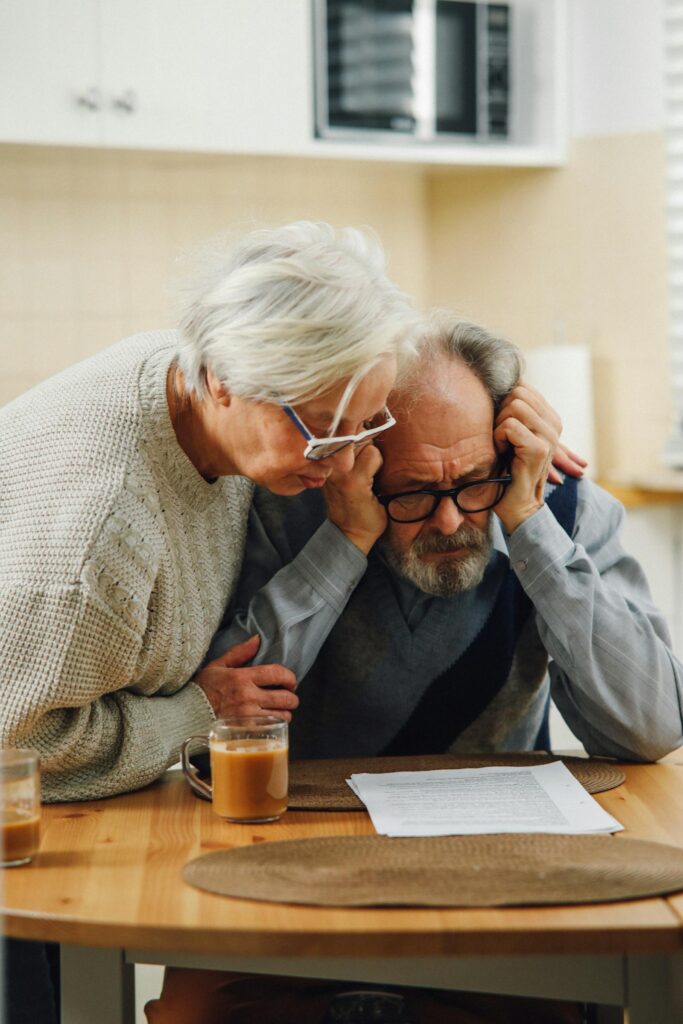A senior couple reviewing paperwork at the kitchen table.