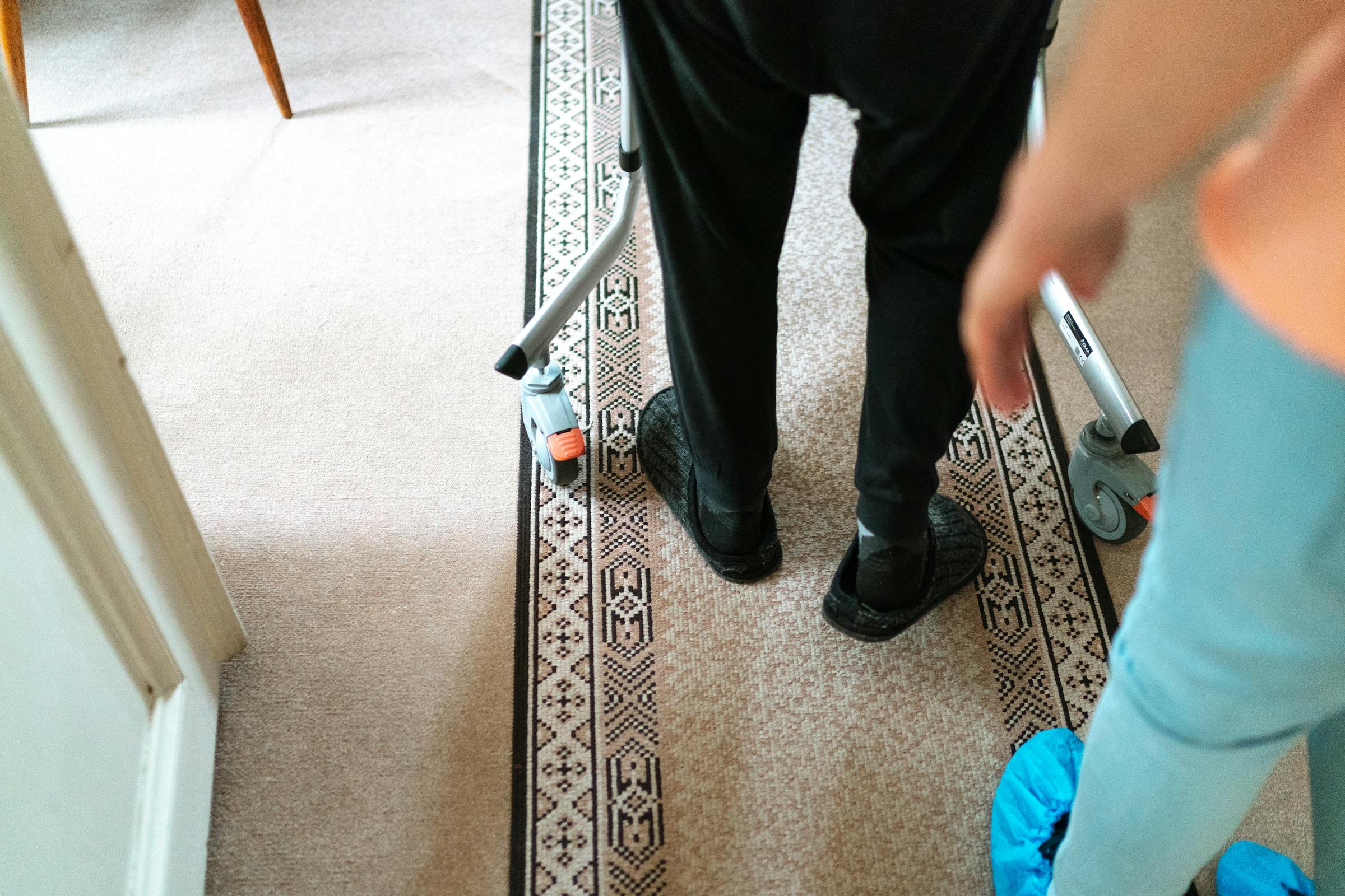 A senior with a walker being assisted by a caregiver in a cozy home setting.